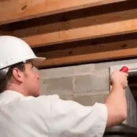 Termite inspection technician checking a basement wall and framing for termite activity in South Bend, IN